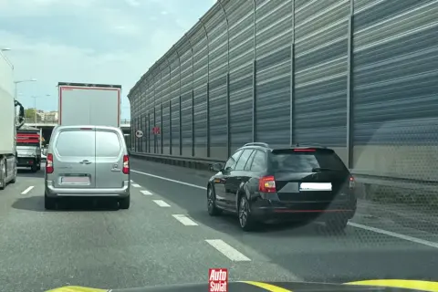 Korki na autostradzie, samochody stoją w rzędzie. Kierowcy czekają na możliwość zjazdu, stosując jazda na suwak.