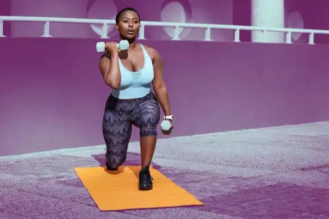 Woman performing lunges with dumbbells, building shoulder endurance exercises.