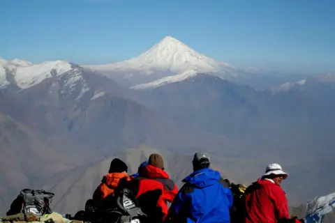 Vier Wanderer blicken auf das majestätische Demavend-Gebirge im Iran.