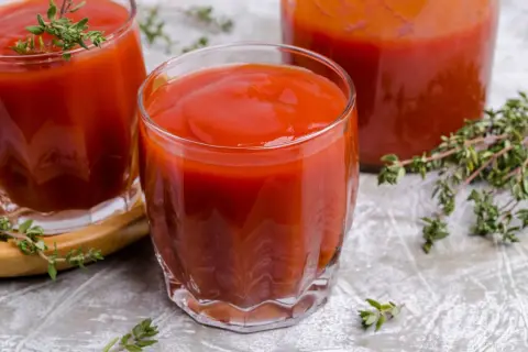 Gęsty, czerwony sok pomidorowy w szklankach, idealny na orzeźwienie. Gałązki tymianku dodają aromatu.