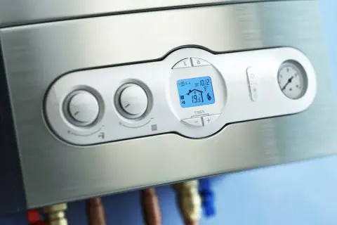 Panel de control de una caldera bomba de calor, con pantalla digital mostrando la temperatura y mandos giratorios.