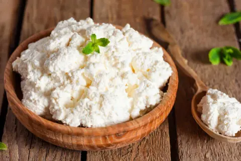 Fiocchi di latte in una ciotola di legno, guarniti con menta. Attenzione, i fiocchi di latte fanno ingrassare se consumati in eccesso!