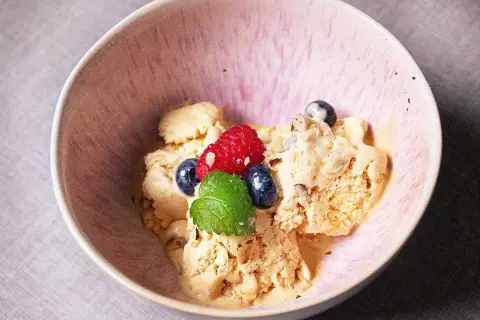 En skål med krämig dulce de leche glass, toppad med färska bär och mynta. En härlig dessert som smälter i munnen.