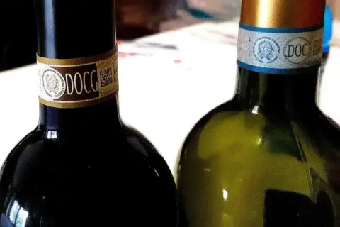 Dwie butelki włoskich win DOCG, czerwonego i białego, gotowe do degustacji.