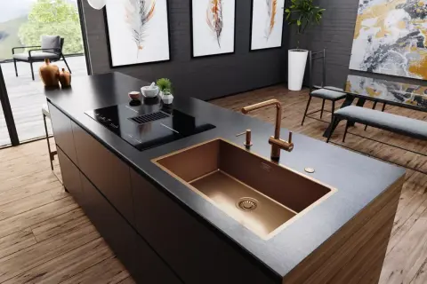 Cocina moderna con isla, placa de inducción y fregadero de cobre. Varios tipos de fregaderos, como este de diseño, realzan la estética.