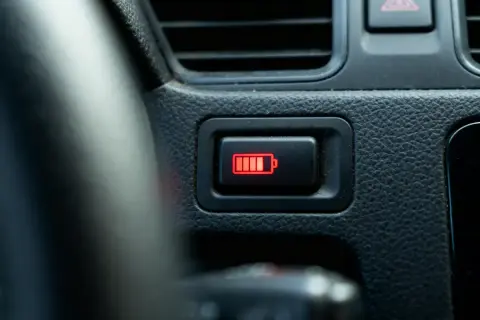 Voyant batterie rouge sur le tableau de bord d'une voiture, indiquant une faible autonomie.
