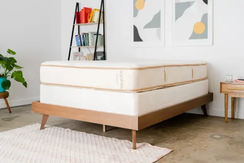 A Saatva mattress on a wooden bed frame, perfect for answering "cual es el mejor colchon para dolor de espalda.