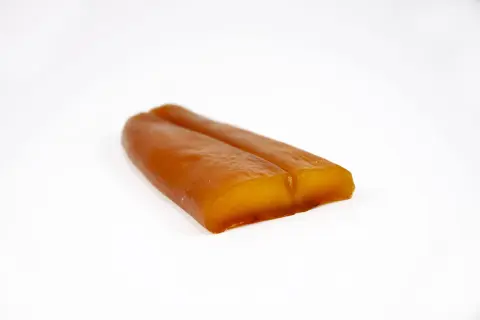 Zwei goldbraune, längliche Stücke Bottarga di Muggine liegen nebeneinander auf weißem Grund.