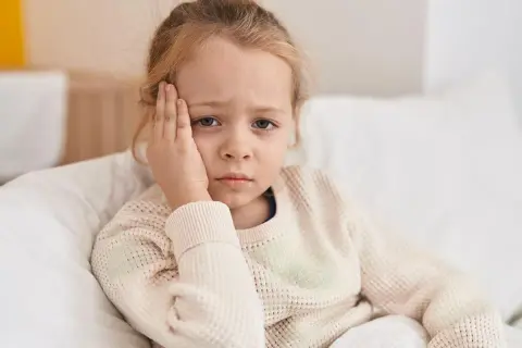 Ein trauriges Kind mit Kopfschmerzen, das sich im Bett ausruht. Vielleicht ist es ein Zeichen für schnelles Wachstum.
