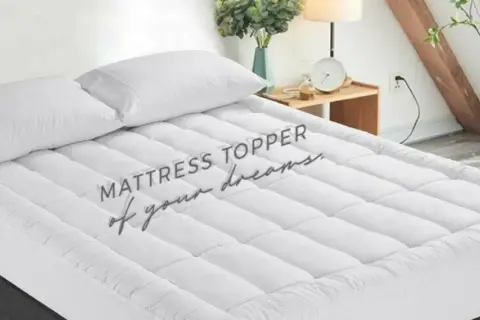 A plush mattress topper with two white pillows sits on a bed, promising a night of sweet dreams.