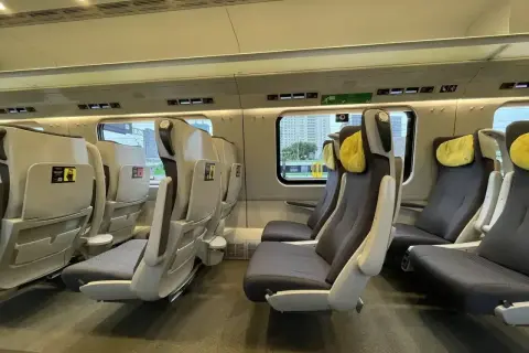 Wygodne fotele w pociągu intercity klasa 1 a 2, z żółtymi zagłówkami, czekają na podróżnych.