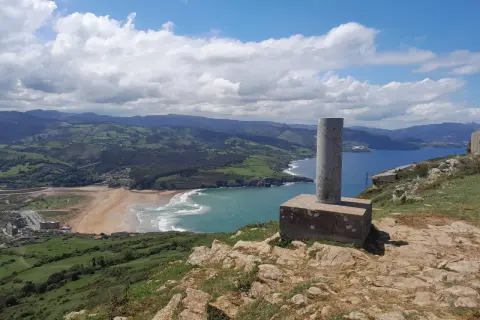 Vistas desde Punta Lucero: costa verde, playa dorada y mar azul bajo un cielo nublado.