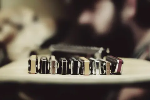 Rząd harmonijek ustnych, w tym taby na harmonijkę c, leży na drewnianym blacie.
