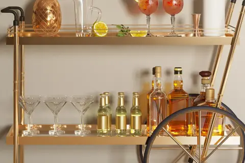 Elegancki barek w salonie z butelkami whisky, kieliszkami do martini i złotym dzbankiem w kształcie ananasa. Pomysły na stylowe przyjęcie.