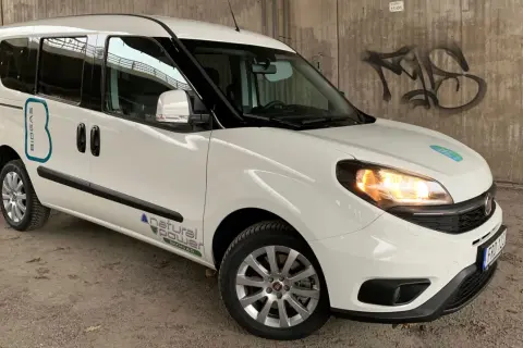Vit Fiat Doblo med texten "BIOGAS" och "natural power" på sidan. En bil med ett potentiellt fiat doblo problem, kanske relaterat till dess biogasdrift.