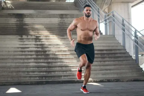 Ein Mann joggt eine Treppe hoch. Beim Joggen werden viele Muskeln trainiert, besonders die Beinmuskulatur.