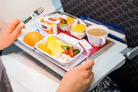 Un pasto aereo con omelette, verdure, pane e caffè. Si può portare cibo in aereo, e questo è un esempio di come viene servito.