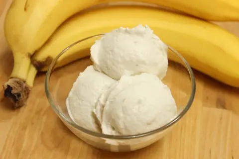 Schon probiert, bananeneis selber machen? Hier ist ein köstliches Ergebnis in einer Schale, daneben reife Bananen.