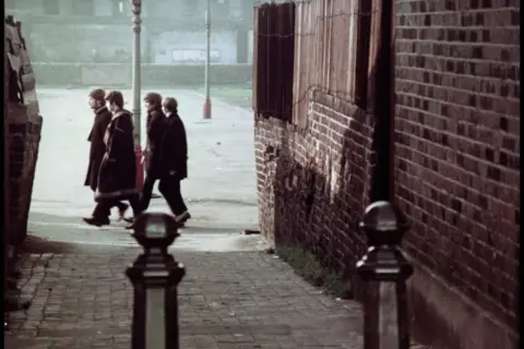 Czterech mężczyzn w płaszczach idzie ulicą Penny Lane.