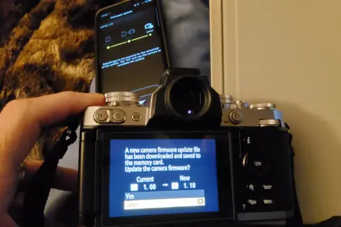 Aktualizacja oprogramowania aparatu Nikon z telefonu. Ekran aparatu pokazuje komunikat o pobraniu pliku aktualizacji i pytanie, czy chcesz zaktualizować oprogramowanie.