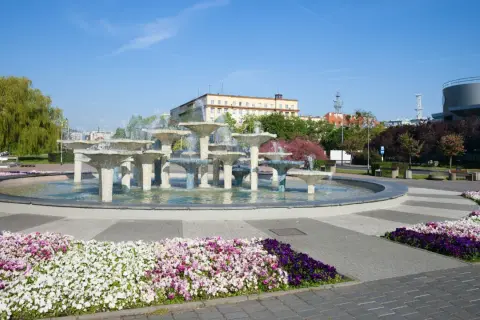 Fontanna w Gdyni, stare miasto, otoczona kolorowymi kwiatami i zielenią.