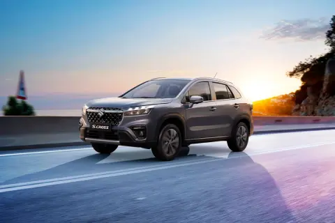 Grå Suzuki S-Cross kör längs en väg vid solnedgången. Inga problem här, bara en vacker resa.
