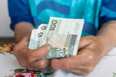 Dłonie trzymają polskie banknoty. Zastanawiasz się, ile wynosi umowa zlecenie na godzinę netto?
