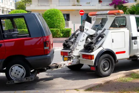 Une dépanneuse enlève une voiture rouge. Une amende pour stationnement illégal a peut-être été émise.