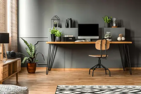 A modern desk setup with a computer, plants, and decorative items. This image shows how to hide cords on desk for a clean, organized workspace.