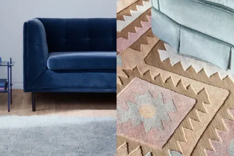 A dark blue sofa next to a light blue rug and a patterned rug with geometric designs.