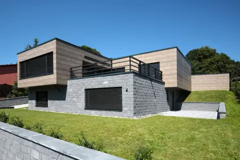 Nowoczesna bryła domu z kamienną podstawą i drewnianą fasadą. Elegancka fasada co to? To wizytówka budynku.