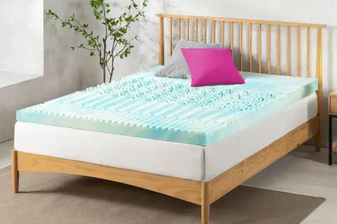 A blue and white memory foam mattress topper with a textured surface sits on a wooden bed frame. Perhaps this is why is my memory foam mattress so uncomfortable.