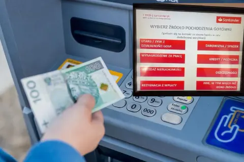 Wpłata BLIK w Santanderze. Ręka z banknotem 100 zł przy bankomacie, ekran wyboru źródła gotówki.