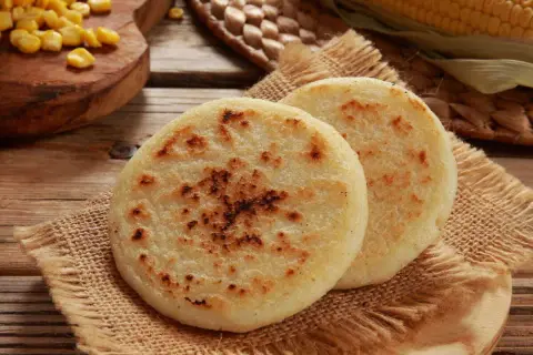 Deux arepas dorées, garnies de maïs, sur une toile de jute. Un délice à déguster !