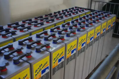 Rzędy baterii do fotowoltaiki, połączonych kablami. Każda bateria ma żółtą etykietę z napisem "dryfit A600 solar".