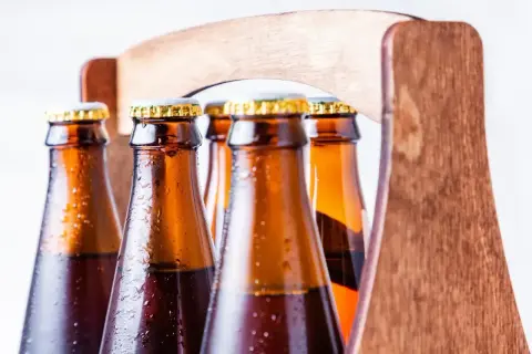 Zimne butelki piwa w drewnianym trayu. Z czego robi się piwo? Z chmielu, słodu i wody, a potem fermentuje.