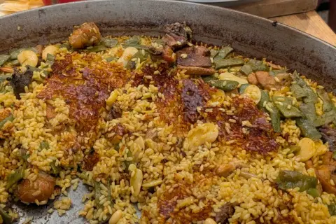 Paella de carne recién hecha, con arroz dorado, trozos de carne tierna, judías verdes y un delicioso socarrat crujiente.