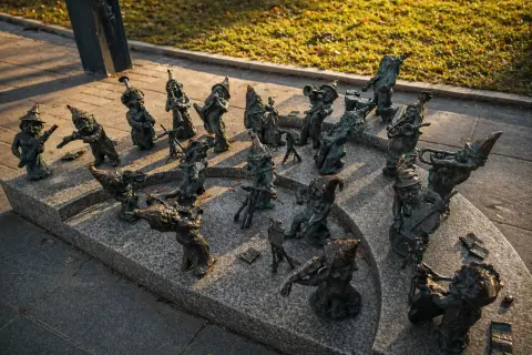 Wrocławskie krasnale, muzycy z brązu, grają na instrumentach na kamiennym postumencie.