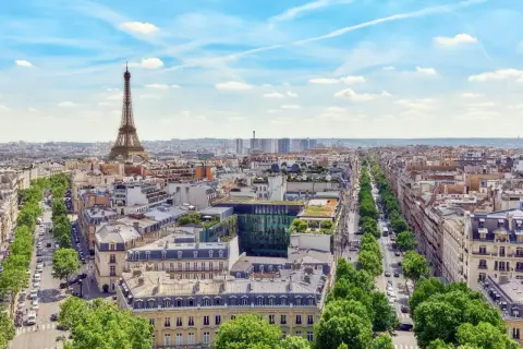 Vy över Paris med Eiffeltornet i fjärran. En grönskande allé leder mot stadens centrum, där takåsarna vittnar om stadens rika historia och många museum.