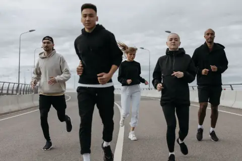 Grupa biegaczy w sportowych strojach. Idealnie, jak się ubrać na 10 stopni: bluzy, spodnie i kurtki.
