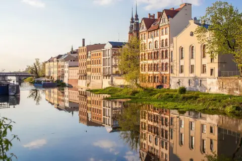 Nad Odrą w Opolu, zabytkowe kamienice odbijają się w spokojnej wodzie. To piękne opole atrakcje, które warto zobaczyć.