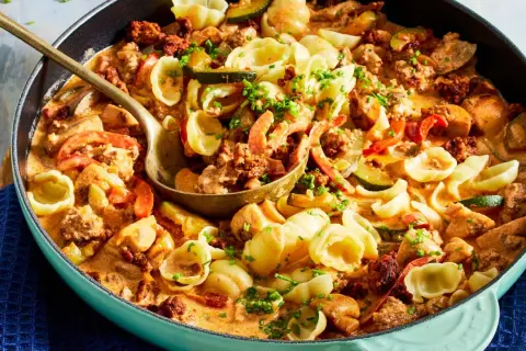 Hackfleisch-Nudel-Pfanne mit Zucchini und Paprika in cremiger Sauce, garniert mit Schnittlauch.
