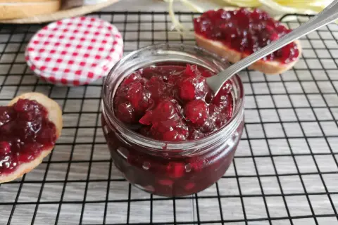 Domowy konfitura z żurawiny przepis. Słoiczek pełen pyszności, obok kromki chleba z żurawiną.
