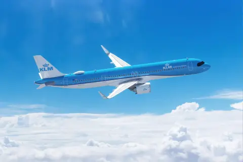 Niebieski Airbus A321 271NX linii KLM majestatycznie leci nad chmurami, symbolizując podróż i odkrycia.