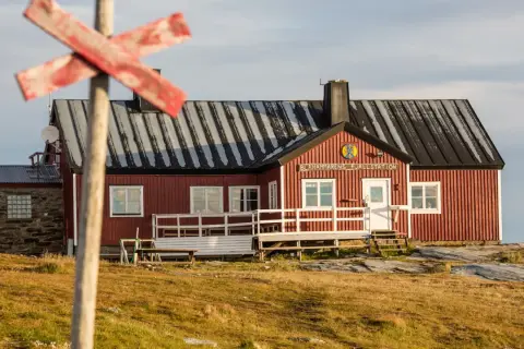 STF Blåhammaren Fjällstation, en röd fjällstuga med vita detaljer, välkomnar vandrare i ett kargt landskap.