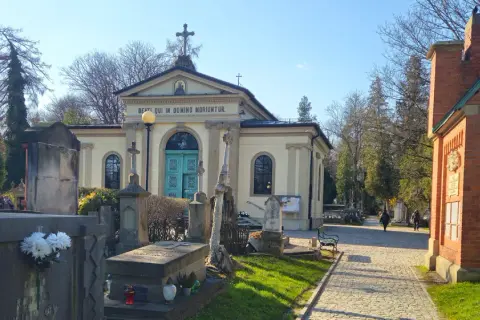 Cmentarz Rakowicki, z kaplicą i nagrobkami, w słoneczny dzień.