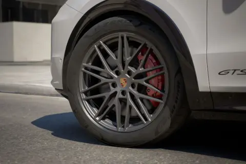 Zbliżenie na koło Porsche Cayenne GTS z czerwonymi zaciskami hamulcowymi i felgą w ciemnym kolorze.