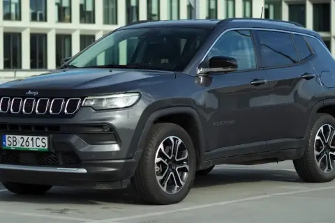 Szary Jeep Compass na parkingu. Wiele osób szuka jeep compass opinie przed zakupem.