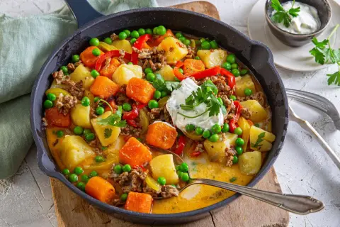 Herzhafte Hackfleischpfanne mit Kartoffeln, Karotten und Erbsen. Eine tolle Idee für ein schnelles Abendessen, garniert mit frischer Petersilie und einem Klecks Sour Cream.