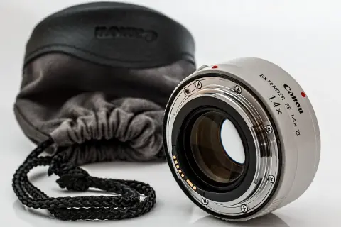 Canon Extender EF 1.4x III, czyli telekonwerter, gotowy do pracy. Obok miękki futerał z logo Canon.